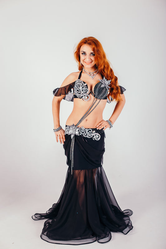 Woman in a black and silver custom belly dance costume with rhinestone details and chiffon skirt