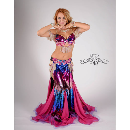 Woman in a custom sequin belly dance costume with fitted mermaid skirt and chiffon inserts in pink and purple-blue gradient

